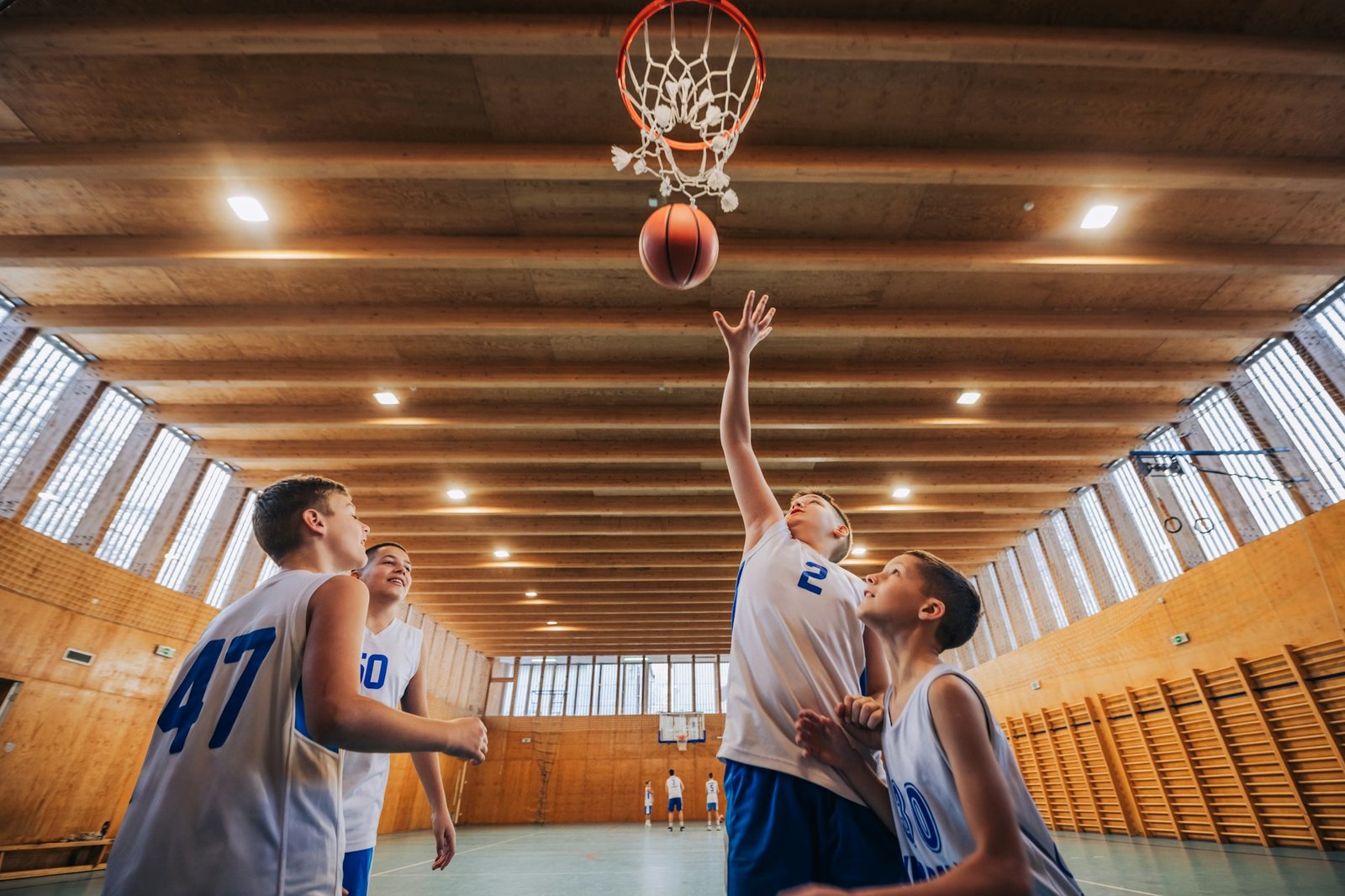 Low angle view of junior basketball team on court shooting at the hoop.